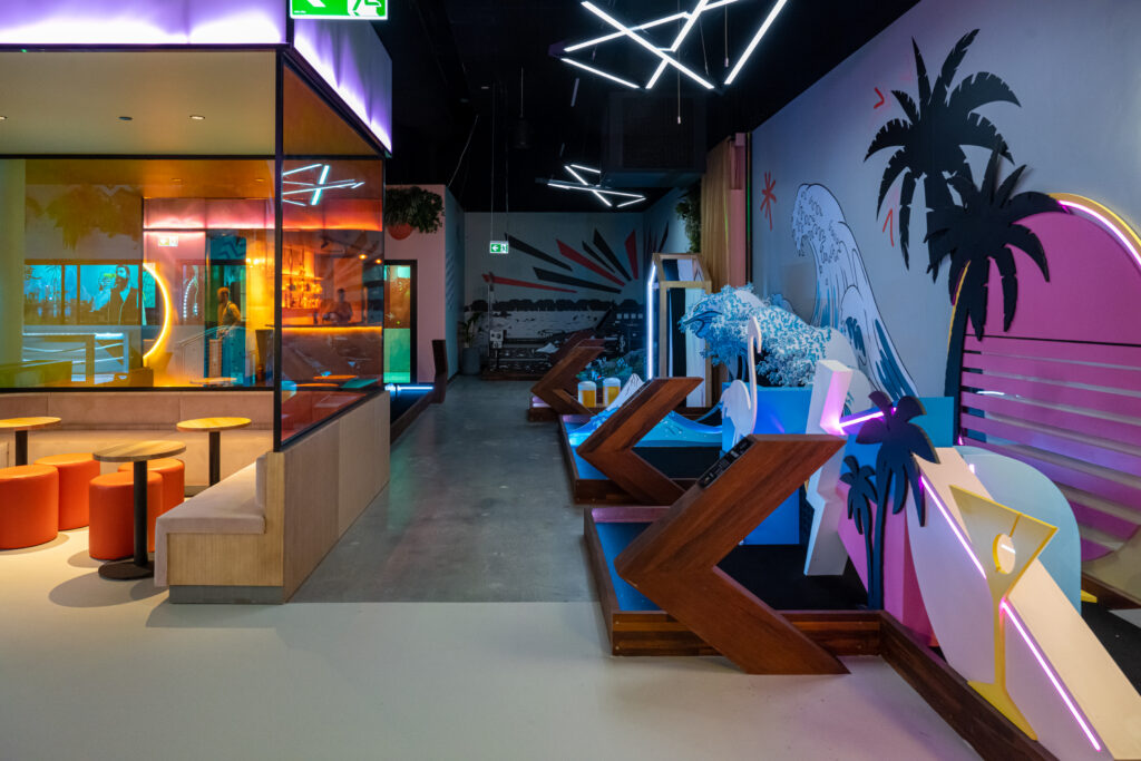 Neon lit mini golf course with tropical accents and angular seating at Hey Caddy venue