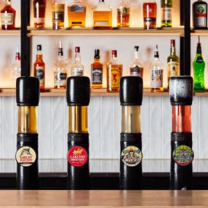 Four draft beer taps lined up on a bar counter with illuminated shelves of spirits and liquor in the background at Hey Caddy.