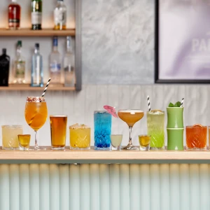 A wide lineup of colorful cocktails, spritzes, beers, and tropical drinks displayed across the bar top at Hey Caddy.