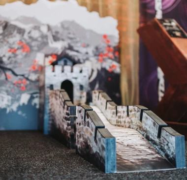 Hey Caddy mini golf hole featuring a Great Wall of China stone bridge obstacle leading through an archway with cherry blossom mural