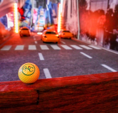 Yellow mini golf ball with Hey Caddy logo on a New York City themed hole with yellow taxis