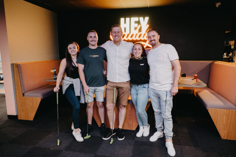 Group of friends posing after indoor mini golf at Hey Caddy Macarthur