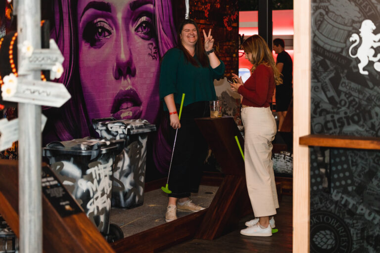 Woman enjoying indoor mini golf with friends at Hey Caddy Marion