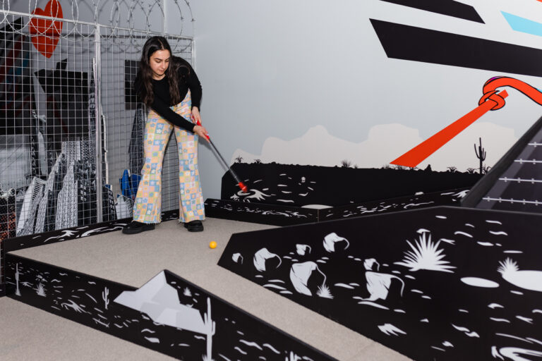 Woman taking a putt on the indoor mini golf course at Hey Caddy Marion