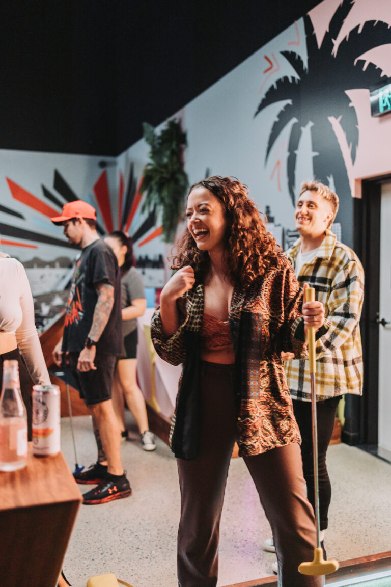 Friends laughing during a social mini golf session at Hey Caddy Townsville