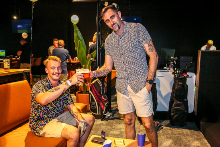 Friends enjoying drinks near the indoor golf area at Hey Caddy Palmerston