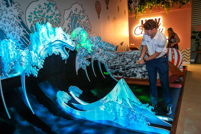 Guest playing a colourful mini golf hole at Hey Caddy Palmerston