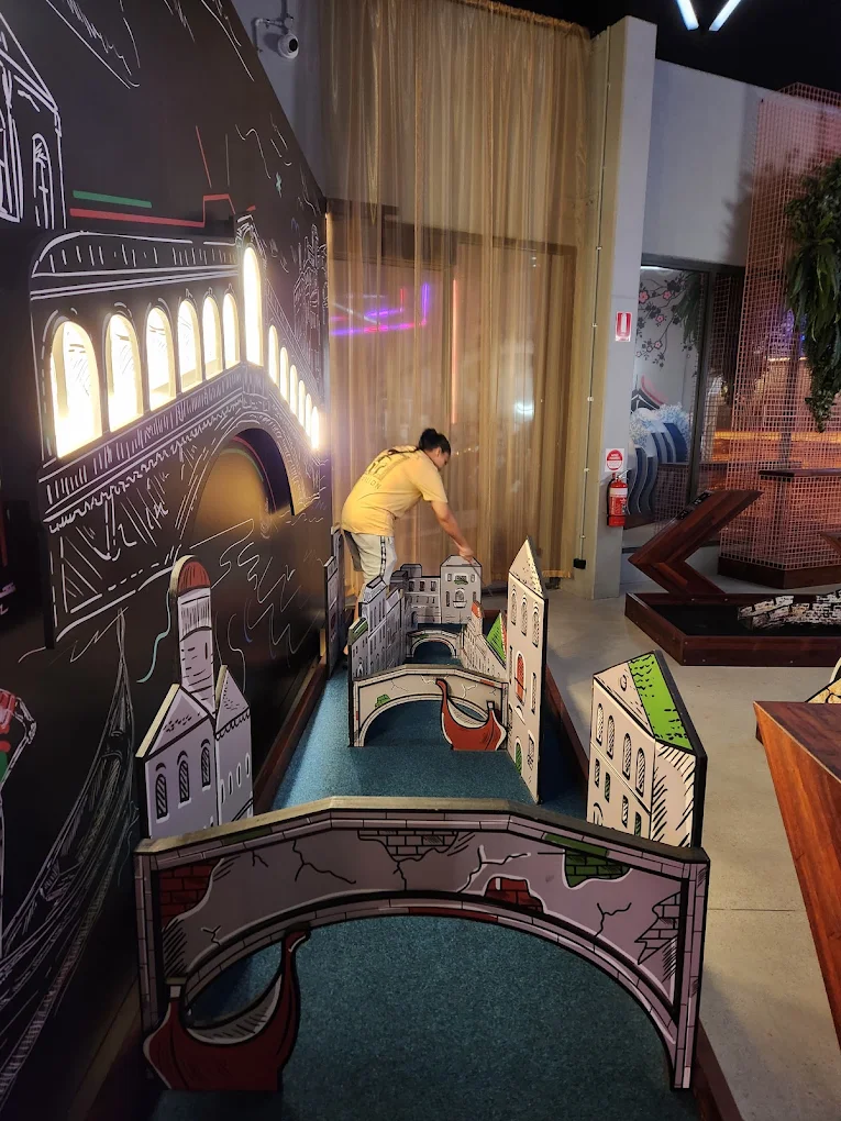 Indoor mini golf lane with city-themed obstacles and bridge features at Hey Caddy North Lakes