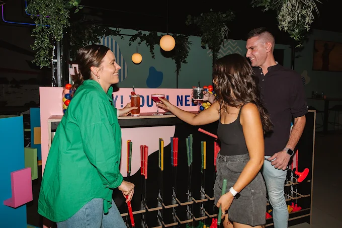 Friends socialising with drinks and mini golf clubs at Hey Caddy South Bank
