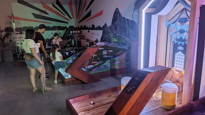 Family playing themed indoor mini golf at Hey Caddy Preston in Melbourne
