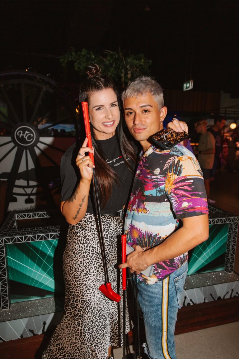 Couple enjoying indoor mini golf beside the feature wheel at Hey Caddy Preston