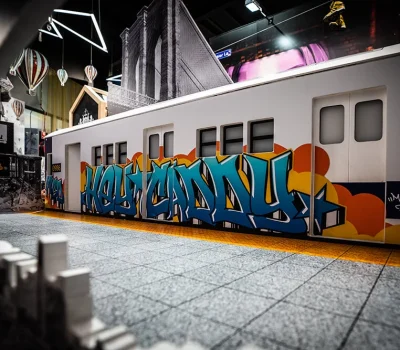 Hey Caddy mini golf features subway train prop with graffiti artwork and city-themed backdrop