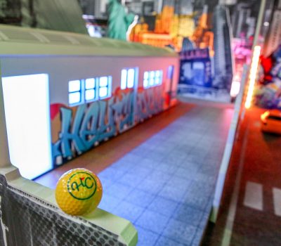Bright hallway with colourful signage and mini golf ball foreground at Hey Caddy venue